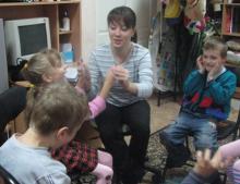 woman holds a blind child by the hand. Next to them are more children