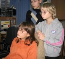 A girl is sitting  in a chair and a man is standing behind her. 